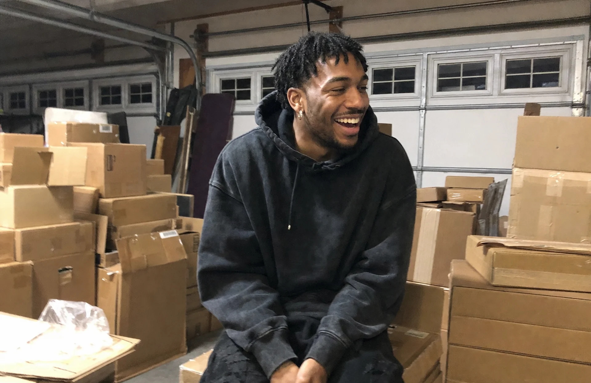 Marcus laughing in his garage among boxes